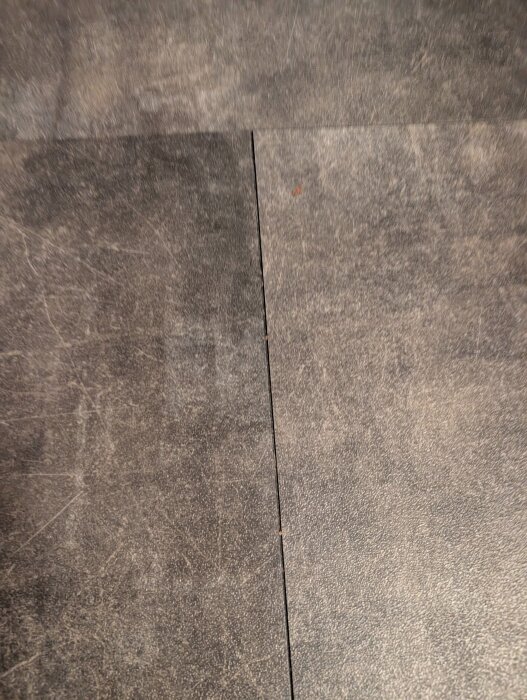 Spruckna vinyl klickgolvplattor i kök, med synliga mellanrum mellan plattorna.