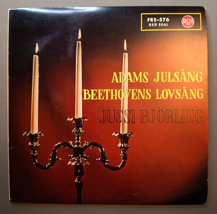 En skivomslagsbild med tre tända ljus i en kandelaber, titeln "Adams julsång Beethovens lovsång" och namnet Jussi Björling i bakgrunden.