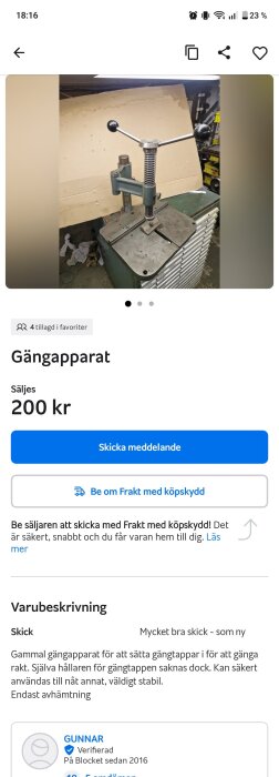 Gängapparat i metall med handtag, placerad på ett arbetsbord. Bakgrund av verkstadsmiljö med pappskiva och hyllor.