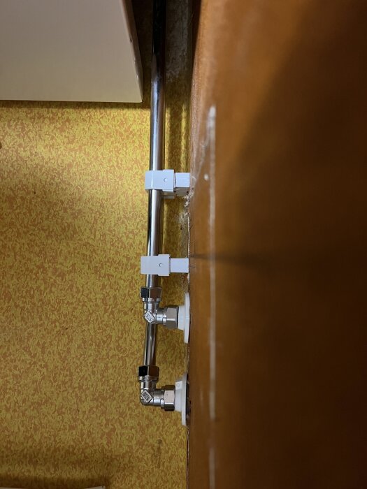 Vattenrör monterade på en vägg med kopplingar som ser sneda ut, vilket representerar dålig installation i ett nyrenoverat badrum.