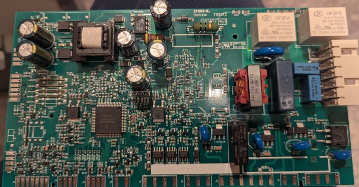 Kretskort med olika komponenter, inklusive kondensatorer och reläer, används troligen i elektroniska apparater för värmestyrning.