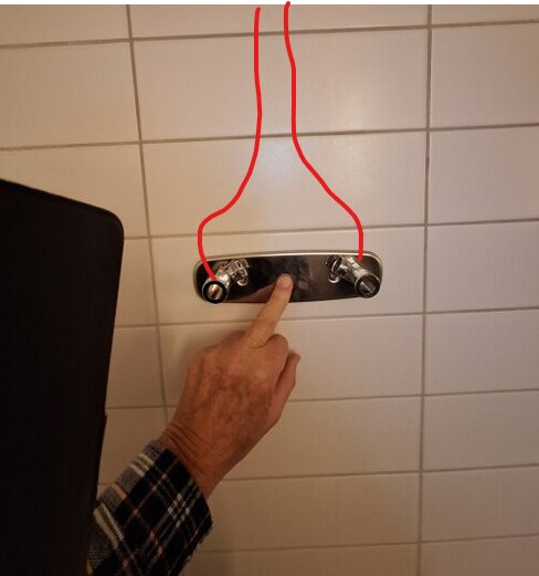 En hand pekar på en vattenkransanslutning på en kaklad vägg. Två röda linjer markerar ledningars möjliga riktning.