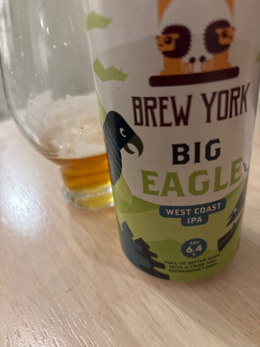 Brew York Big Eagle West Coast IPA-burk och glas med öl på träbord.