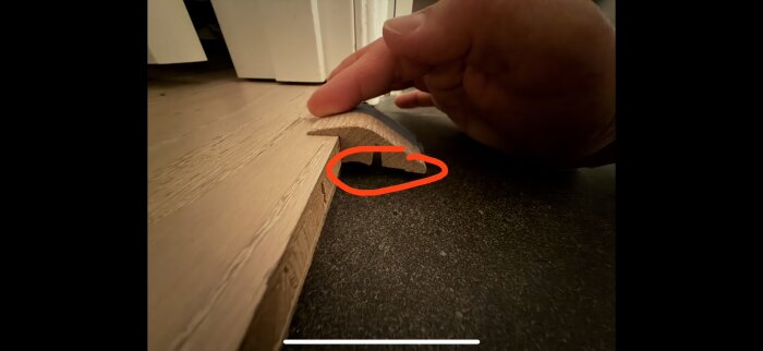 En upphöjd tröskel med ett hål, markerat med rött. En hand pekar på området för möjligt fyllningsmaterial i gör-det-själv-projekt.