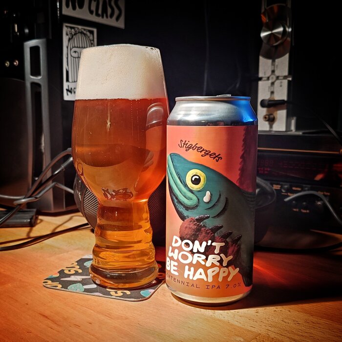 Ölglas och ölburk märkta "Don't Worry Be Happy" i en hemmamiljö.