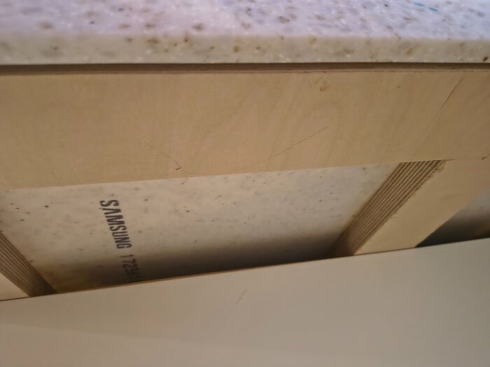 Förstärkning under en bänkskiva med synliga fogar och ett Samsung-märke.