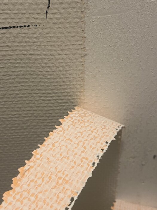 Vävtapet avlägsnas från väggen i en lägenhet byggd 1980, detalj av tapetstruktur.