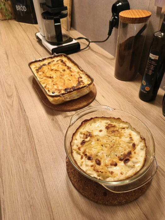 Två gratänger, en rund och en rektangulär, placerade på underlägg i ett kök.