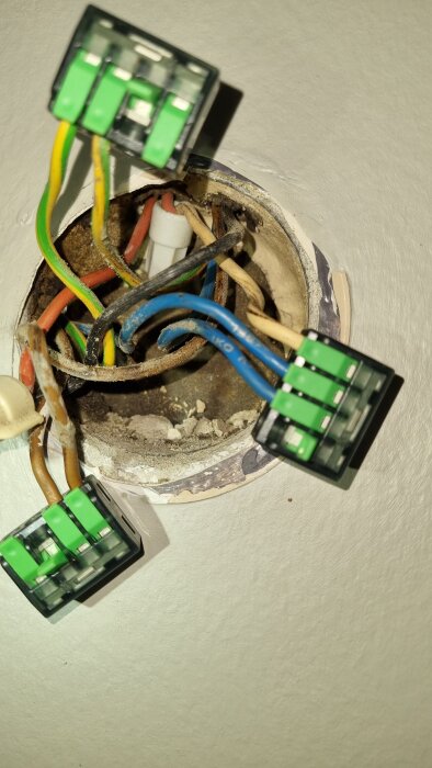 Elektrisk kopplingsdosa i ett badrum, visar flera kablar, inklusive jordade och toppklämmor, i en äldre installation från 1956.