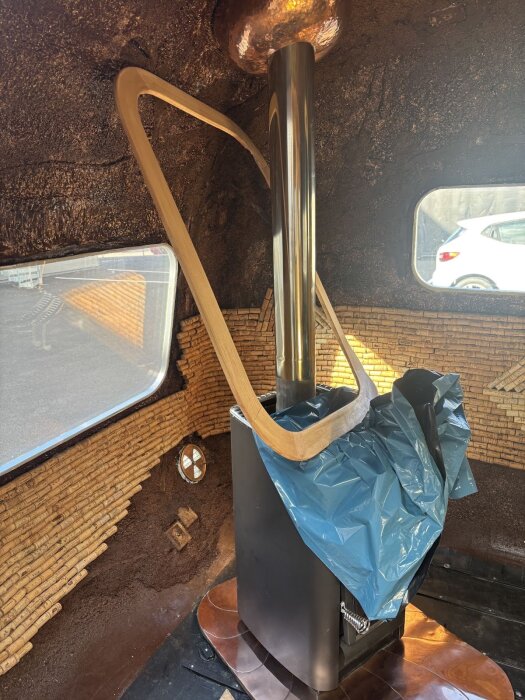 Aggregat med metallrör i rum under golvrenovering, omgiven av fönster och tegelväggar, delvis täckt med plast och träram på plats. Bil utanför.