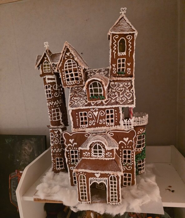 En detaljerad pepparkaksbyggnad med flera torn och fönster dekorerade med glasyr, som ser ut som ett sagoslott.
