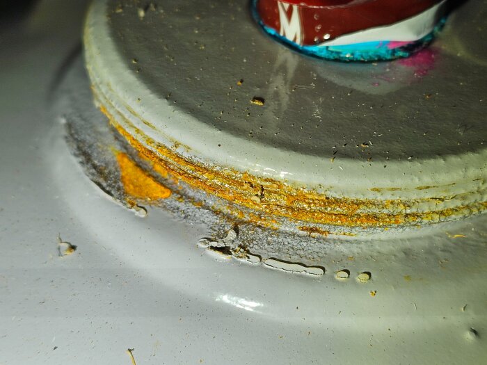 Närbild av en gasolflaskas övre yta, med synlig ytrost i olika lager. Flaskans färg är blekt och rostfläckarna framträder tydligt.