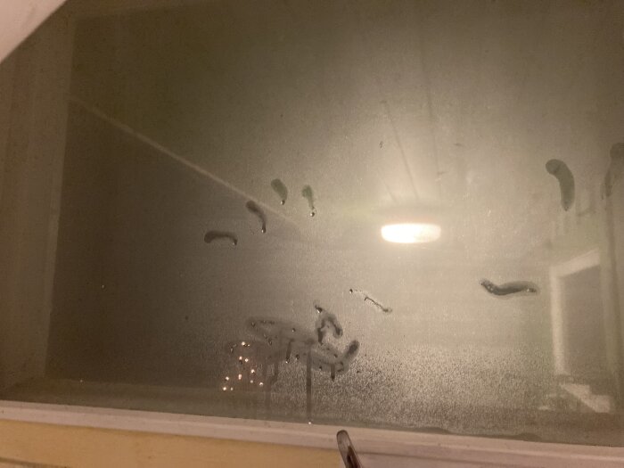 Kondens på glasrutan i ett badrumsfönster, med imma och vattendroppar tydligt synliga på insidan av innerfönsterbågen.