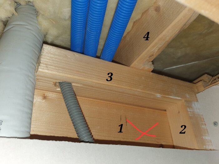 Väggregel och bärlina med märkningar 1-4. Rör och isolering syns kring träreglarna. Nummer 1 är markerad med ett rött kryss.
