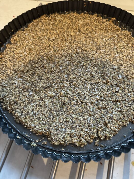 Fröknäcke botten till cheesecake, gjord av pumpakärnor, solroskärnor, linfrön och chiafrön, i en pajform.
