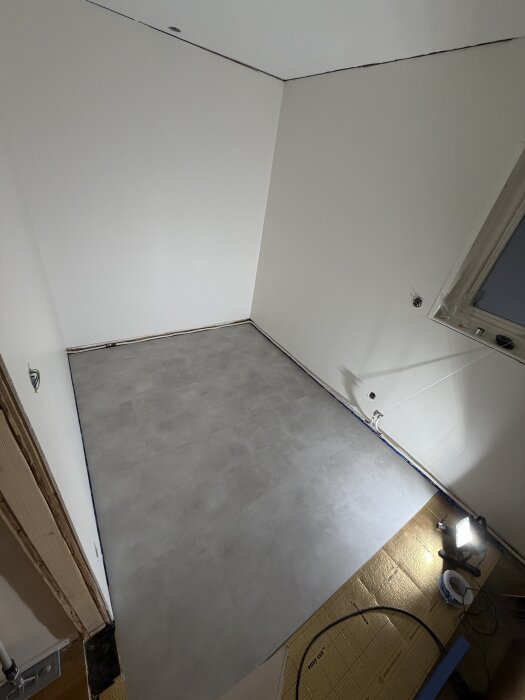 Blågrått vinylgolv i barnrum, installerat från ter Hürne. Kall belysning påverkar färguppfattningen. Väggar i äggskalsvit färg.