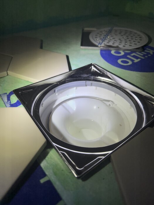 Klinkerram av märket Purus Tile Square placerad på golvplattor, förberedelse för badrumsinstallation.