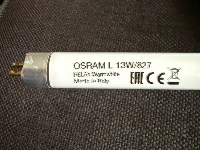 Lysrör från Osram, modell L 13W/827, med texten "RELAX Warmwhite", tillverkat i Italien, visar CE-märkning och varning för avfallshantering.