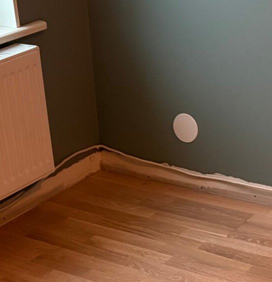 Vägg med doslock och golv av trä intill ett element.