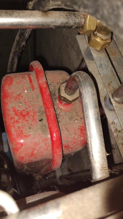 Rött expansionskärl med rör och ventiler i en fjärrvärmecentral. Synlig smuts. Problem med tryck och läckande vatten vid ventilen.