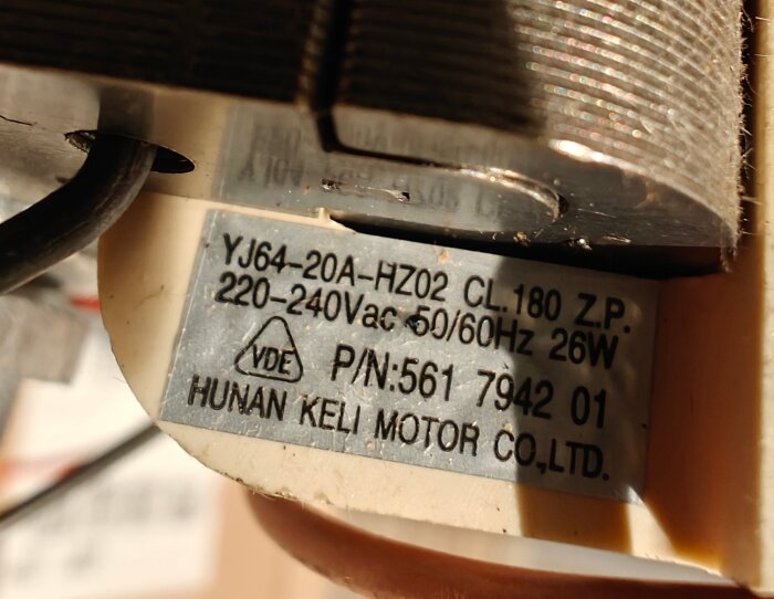 Närbild på en etikett på en motor från Human Keli Motor Co., med specifikationer som spänning 220-240Vac och modellnummer YJ64-20A-HZ02.