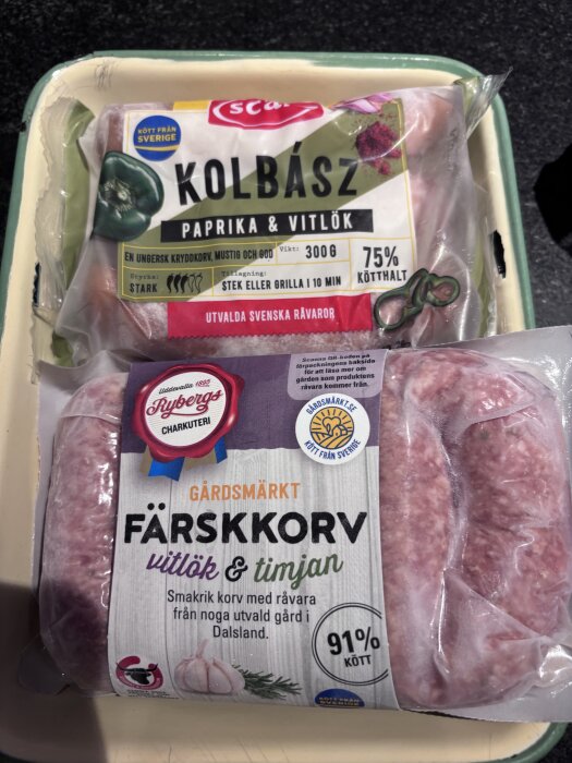Förpackningar med Kolbász korv med paprika och vitlök samt färskkorv med vitlök och timjan på en bricka.