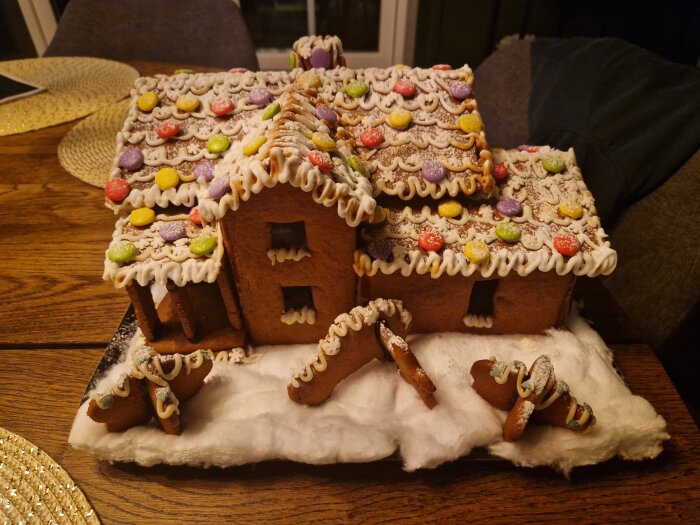 Pepparkakshus dekorerat med färgglatt godis och glasyr, föreställande en modell av ett hem, placerat på ett bord.