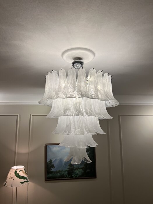 Ljuskrona med hängande glasdetaljer i vardagsrum, ger en elegant och dekorativ belysning.