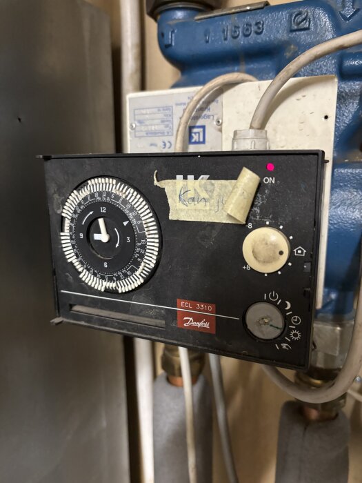 Danfoss ECL 3310 styrning med klocka och sladdar anslutna, monterad på blå enhet i teknisk installation.