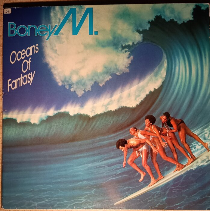 Psykedeliskt LP-omslag från Boney M, visar fyra personer som surfar på en stor våg under himmel med moln. Texten "Oceans of Fantasy" syns.