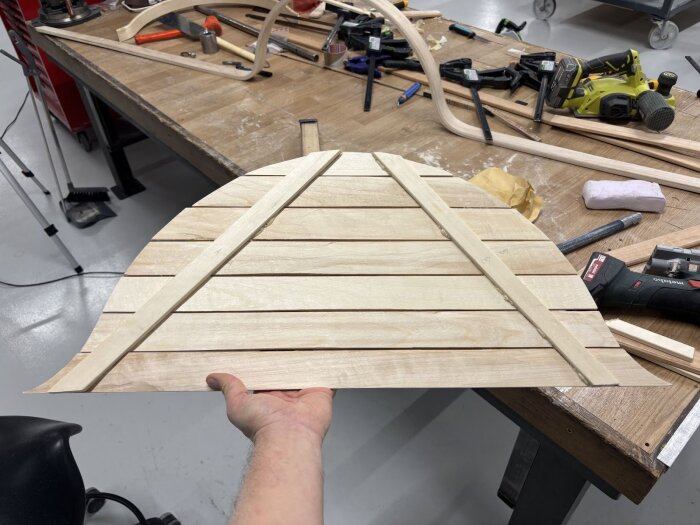 Träpanel till hjulhus under arbete liggande på en arbetsbänk med verktyg och material i bakgrunden.