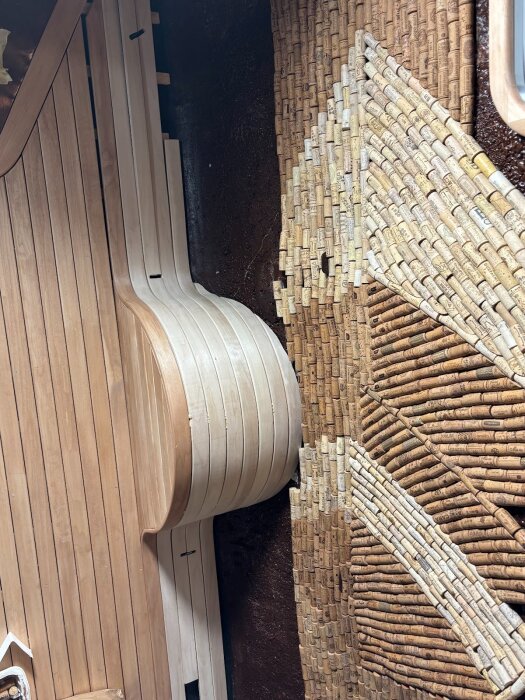 Träribbor och korkar arrangerade i ett unikt mönster runt hjulhusstrukturen, del av byggprojekt under bänk med fokus på detaljer och estetik.
