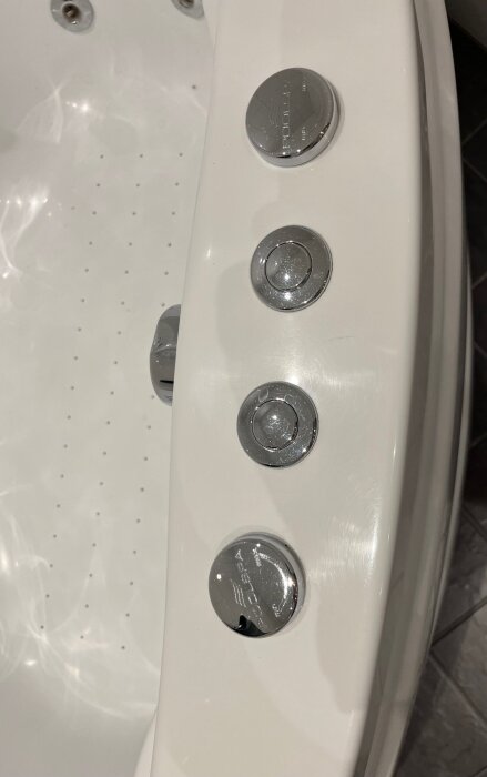 Kontrollpanel på bubbelbadkar med tre kromknappar, varav en märkt "PoolSpa".