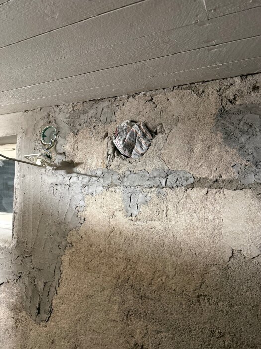 Vägg med hål täckt av tidningar, tidigare plats för tallriksventil i behov av renovering eller byte till annan ventilationslösning.