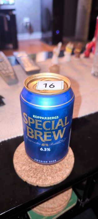 Blå burk med Kopparbergs Special Brew-öl, 6,3% alkoholhalt. Burken står på en korkunderlägg med en nummerlapp "16" ovanpå.