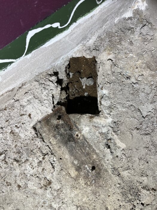 Hål i betonggolv i 70-tals hus med exponerad träbalk och omgivande sprickor, upptäckt vid renoveringsarbete.