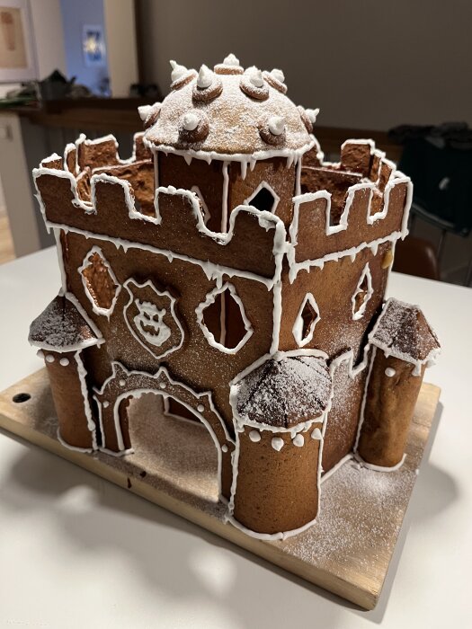 Pepparkakshus föreställande Bowsers borg, dekorerat med vit glasyr och detaljer som torn och tinnar, står på en träplatta.
