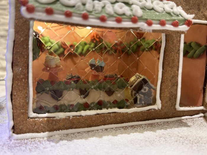 Pepparkakshus med dekorerat skyltfönster som visar butiker inuti. Varmt ljus, snirkliga kakor och fönsternät, del av ett barnvänligt tema.