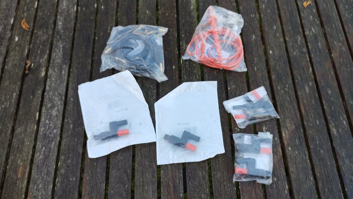Kablage och kontakter i olika plastpåsar placerade på en träbänk utomhus.