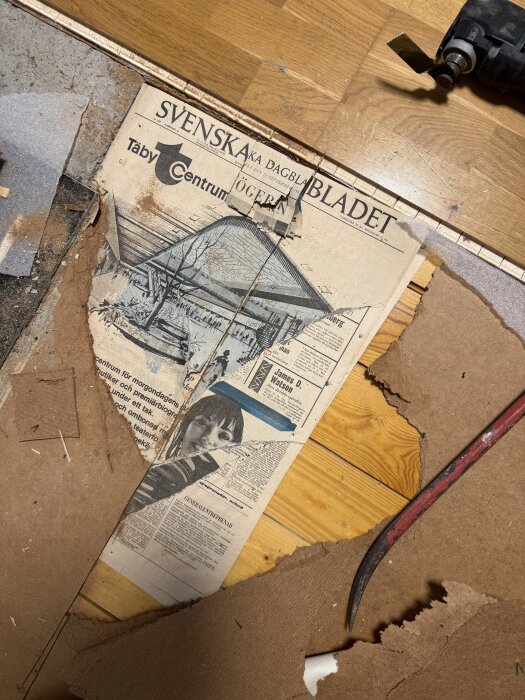 Gammal tidning från 25 september 1968 synlig under ett uppbrutet golv med verktyg runtom, avslöjad vid renovering i en gillestuga.