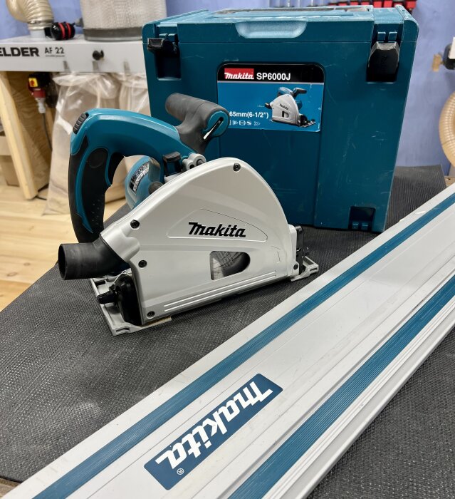 Cirkelsåg Makita SP6000J med skena och systainer i bakgrunden, synliga repor på skenan.