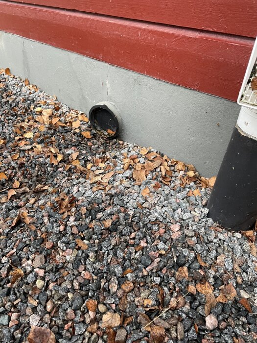 Mysko rör som kommer ut ur grunden på ett hus från 1972, omgivet av sten och löv, i Åtvidabergs kommun.