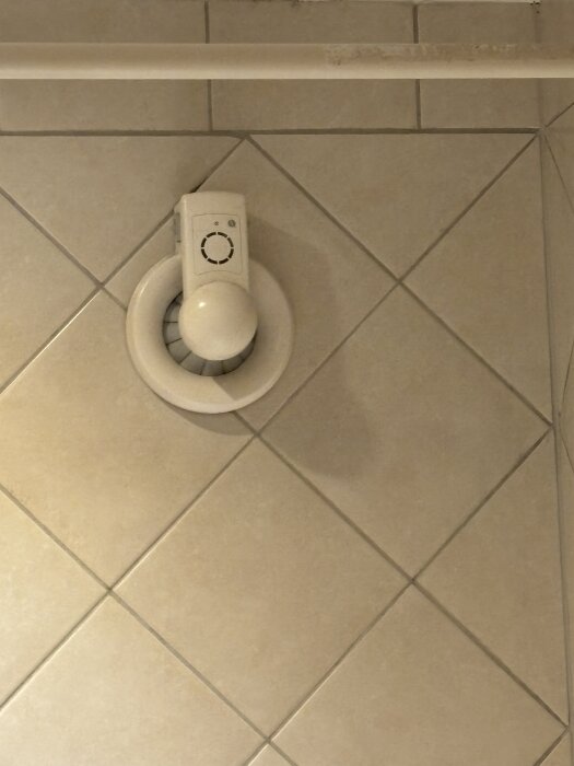 Badrumsfläkt installerad i kaklad vägg. Person funderar på att ersätta den med ett ändlock på grund av nytt FTX-system.