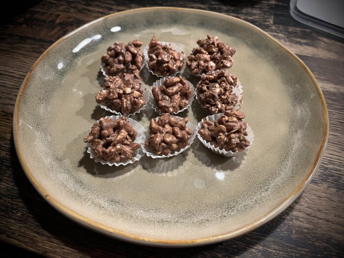 Chokladbitar med rispuffar och apelsinkrokant på en tallrik, toppade med crunchy naturella flingor, serverade i små pappersformar.