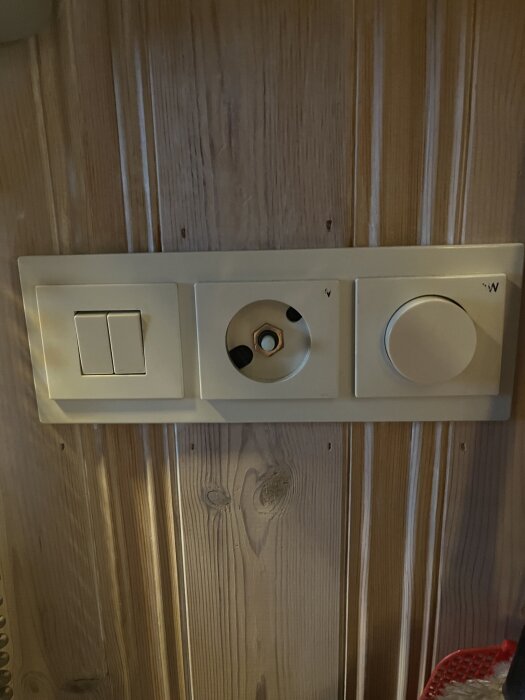 Vit dimmer och strömbrytare på träpanelvägg, med borttagen glassäkring som söker rätt storlek för att lösa problem med flimrande ledlampor.
