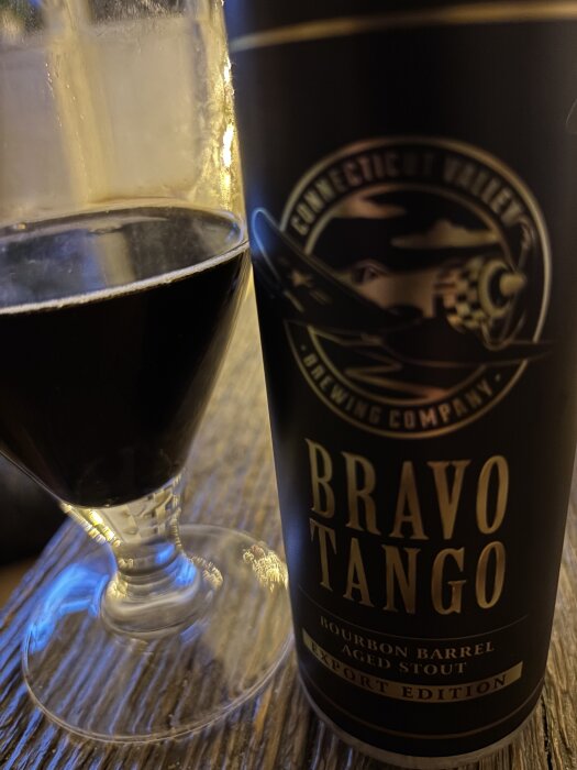 Stoutglas bredvid burk med etiketten "Bravo Tango Bourbon Barrel Aged Stout Export Edition" från Connecticut Valley Brewing Company.