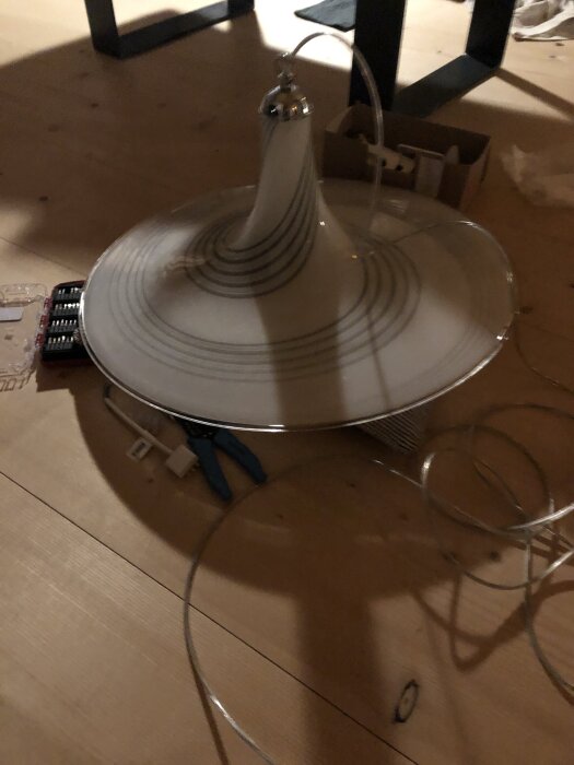 Modell av en lampa med sladd och verktyg för installation.