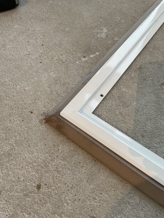 Vit metallram med en ram av MDF på ett betonggolv, förklarar anpassningslösning vid renoveringsprojekt.