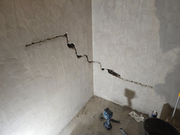 Spricka i en vägg i källare under renovering, omgiven av verktyg.