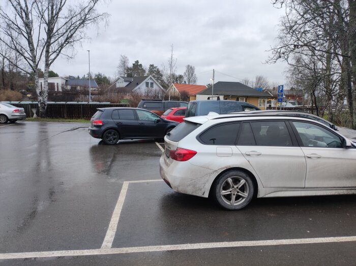 Svart Golf felparkerad diagonalt på parkeringsplats, ser ut att vara på väg ut, andra bilar och hus syns i bakgrunden.